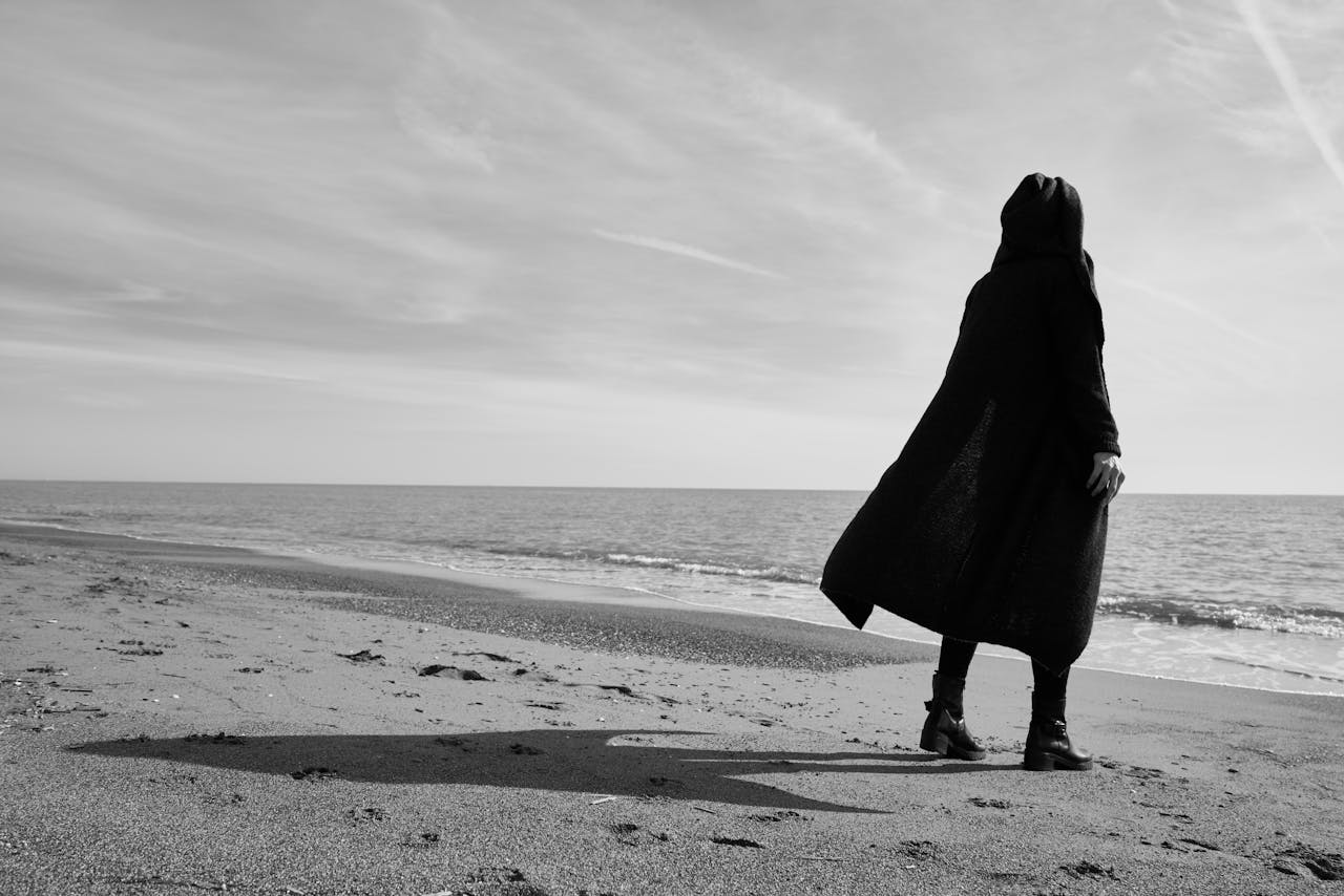 Black and white image of a solitary figure on a beach, evoking emotion and solitude.